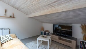 Un salon moderne avec un téléviseur à écran plat, un canapé, une table basse et une bibliothèque.