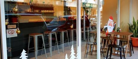 Um restaurante com fachada de vidro, mesas ao ar livre e decoração de árvore de Natal.