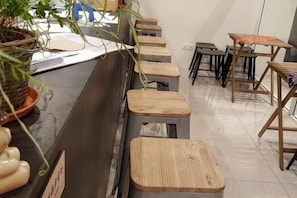 A reception area with a counter, wooden stools, and a potted plant. - Casa Casa Guesthouse Semporna (Semporna)