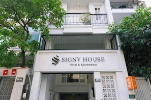 Entrada de un hotel con un letrero que dice 'Signy House Hotel & Apartments'.