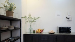 A kitchen with dark cabinets, a microwave, a fruit bowl, and a vase with flowers. - Signy House Sai Gon Center - Nguyen Binh Khiem (Ho Chi Minh City)