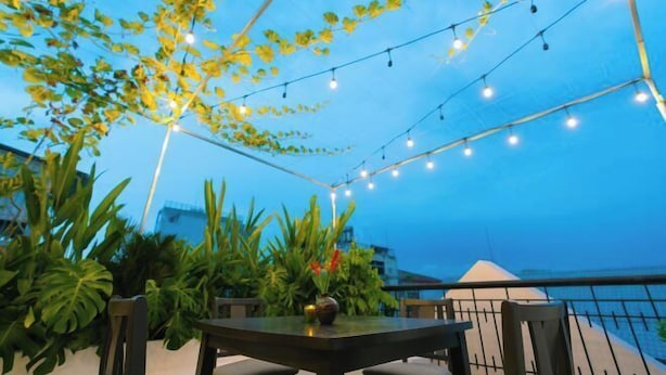 An outdoor patio with a table and chairs, string lights, and lush greenery. - Signy House Sai Gon Center - Nguyen Binh Khiem (Ho Chi Minh City)