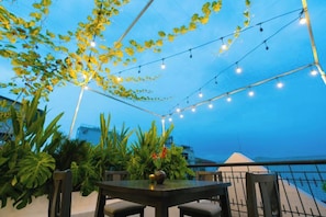 An outdoor dining area with string lights, potted plants, and a view of the city skyline. - Signy House Sai Gon Center - Nguyen Binh Khiem (Ho Chi Minh City)