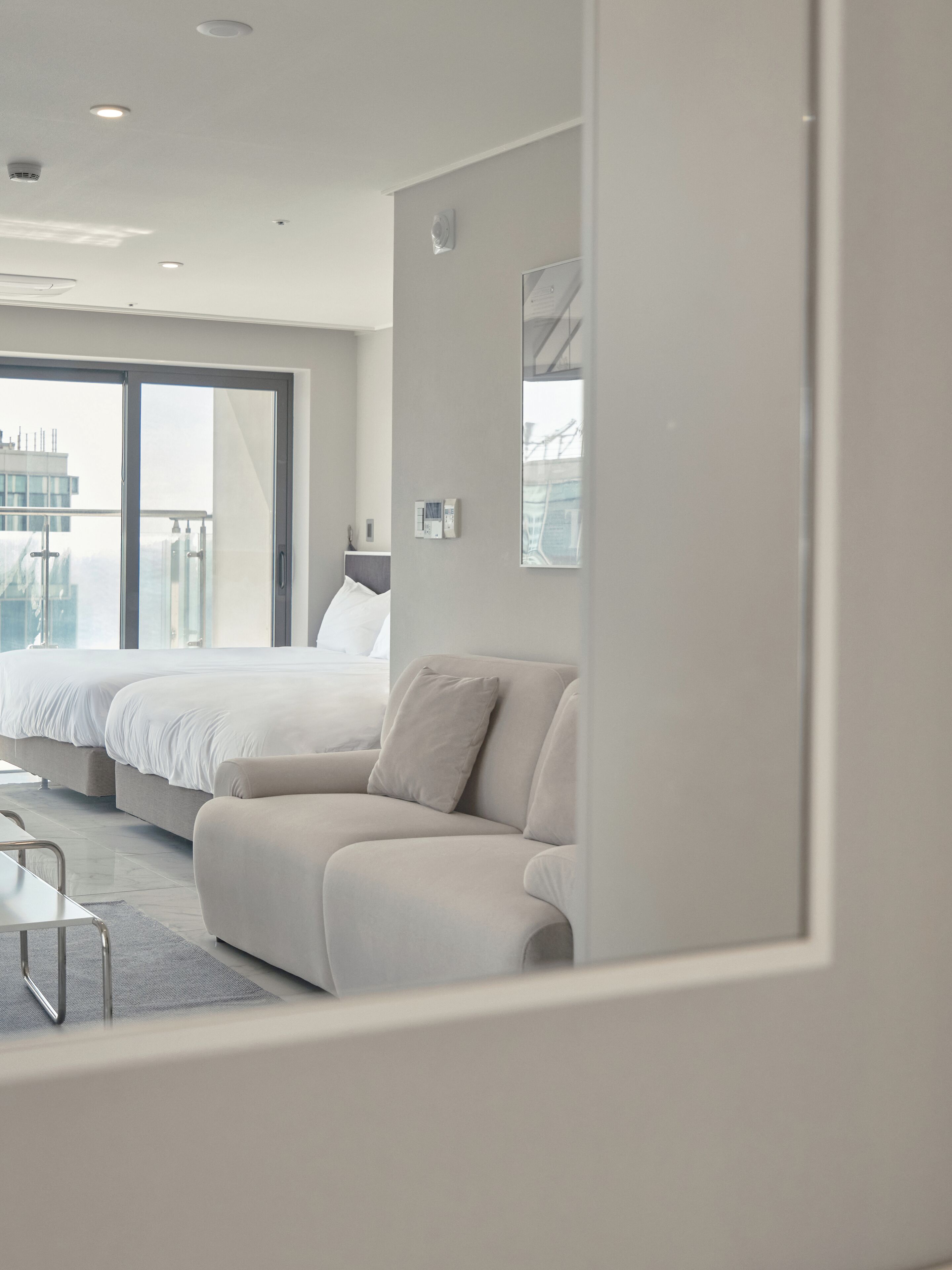 Habitación de hotel moderna con una cama grande, un sofá y vistas a la ciudad a través de la ventana.
