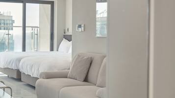Habitación de hotel moderna con una cama grande, un sofá y vistas a la ciudad a través de la ventana.