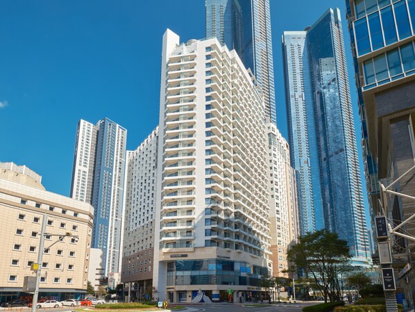 Ein modernes Hochhaus mit einem markanten, winkelförmigen Design, umgeben von anderen hohen Wolkenkratzern.