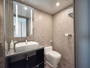 Ein modernes Badezimmer mit großem Spiegel, Waschbecken, Toilette und Duschbereich.
