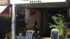 A hostel named "The Moment Hostel" with a signboard, a welcome sign, and a menu board outside. - The Moment hostel (Bangkok)