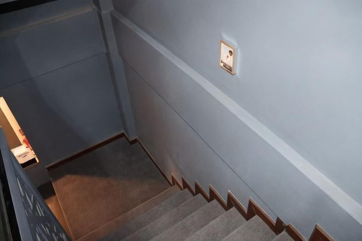 A staircase with carpeted steps and a light switch on the wall.