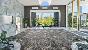 A spacious lobby with a patterned carpet, large windows, and indoor plants. - Main Beach 3-Bedroom Apartment with Ocean Views (Main Beach)