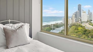 A bedroom with a large window overlooking a cityscape and the ocean. - Main Beach 3-Bedroom Apartment with Ocean Views (Main Beach)