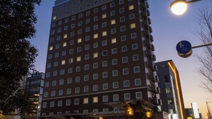 A multi-story hotel with a prominent sign at the top, multiple windows, and a street lamp nearby. - Toyoko Inn Tokorozawa-eki Nishi-guchi (Tokorozawa)