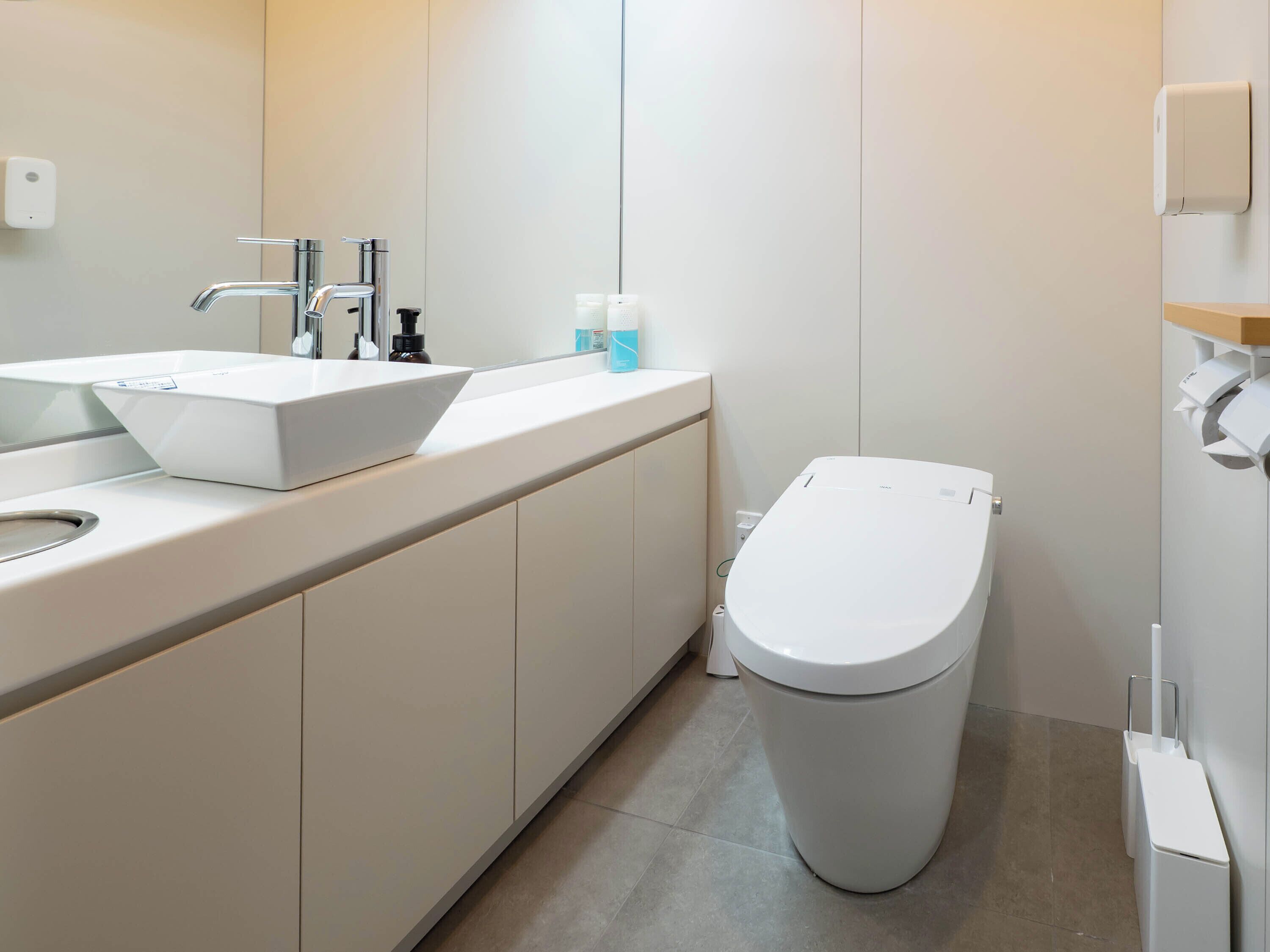 A modern bathroom with a white sink, faucet, and toilet.