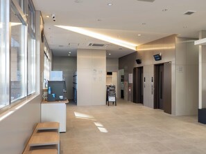 Un moderno vestíbulo de hotel con mostrador de recepción, zona de estar y ascensor.