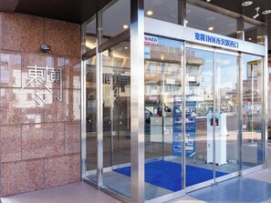 Entrada de un edificio con puertas de vidrio, una alfombra azul y un cartel que indica un centro médico.