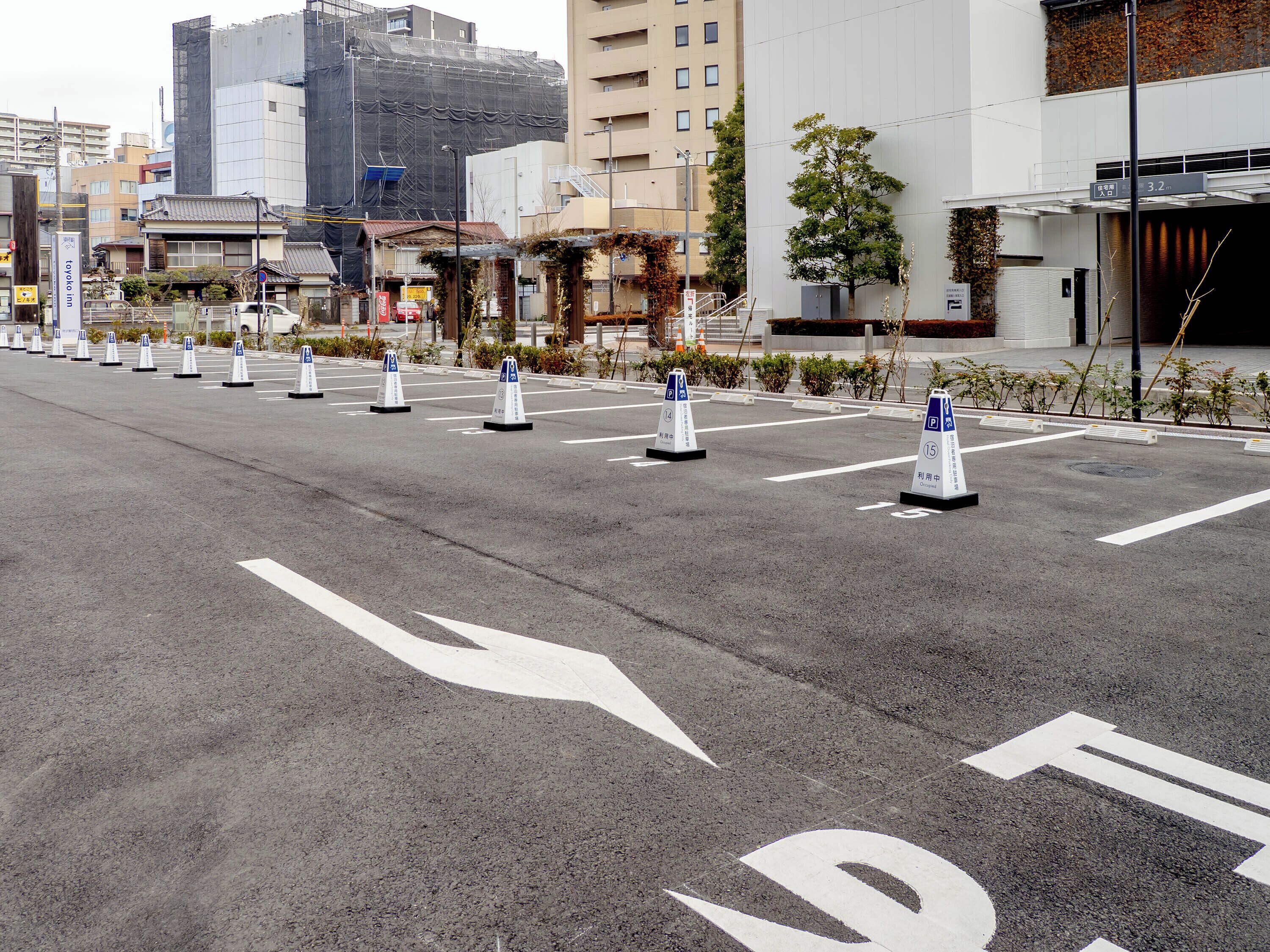 A parking lot with marked spaces and directional arrows on the pavement.