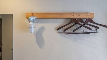 A wall-mounted wooden rack with three brown hangers and a white spray bottle.