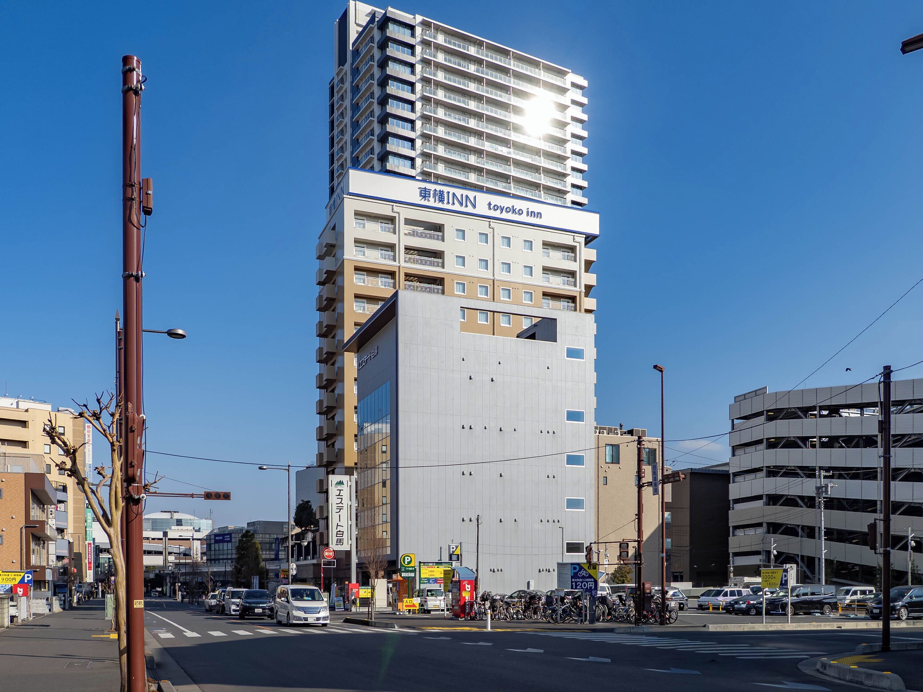 A multi-story building with a prominent sign for 'Toyoko Inn' and a parking sign indicating a 120-minute parking limit.