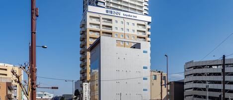 A multi-story building with a prominent sign for 'Toyoko Inn' and a parking sign indicating a 120-minute parking limit.