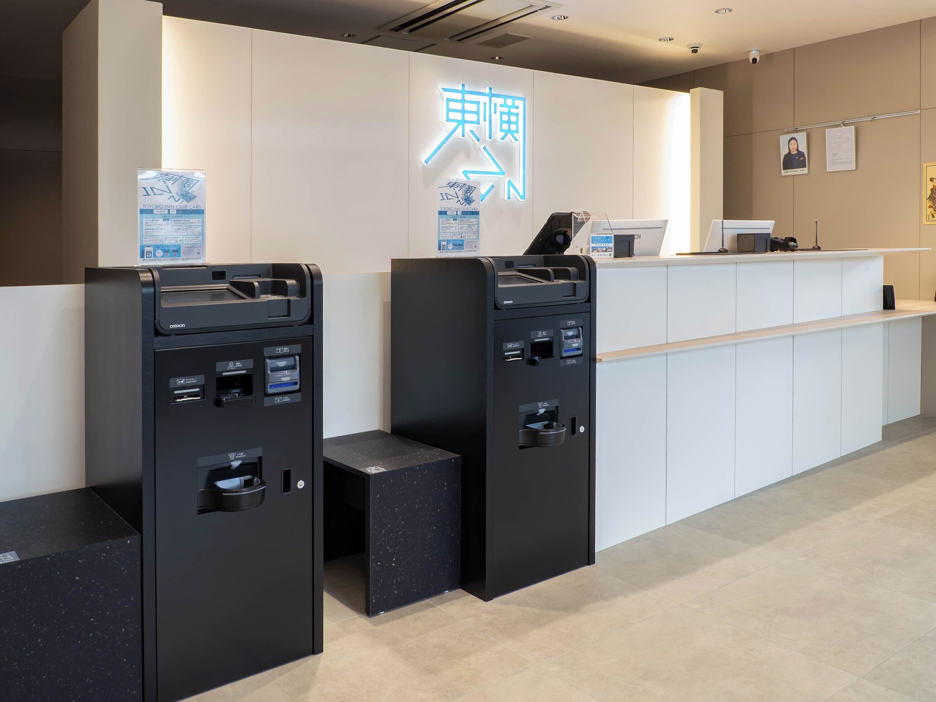 A hotel reception area with ATMs, a reception desk, and a neon sign.