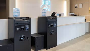A hotel reception area with ATMs, a reception desk, and a neon sign.