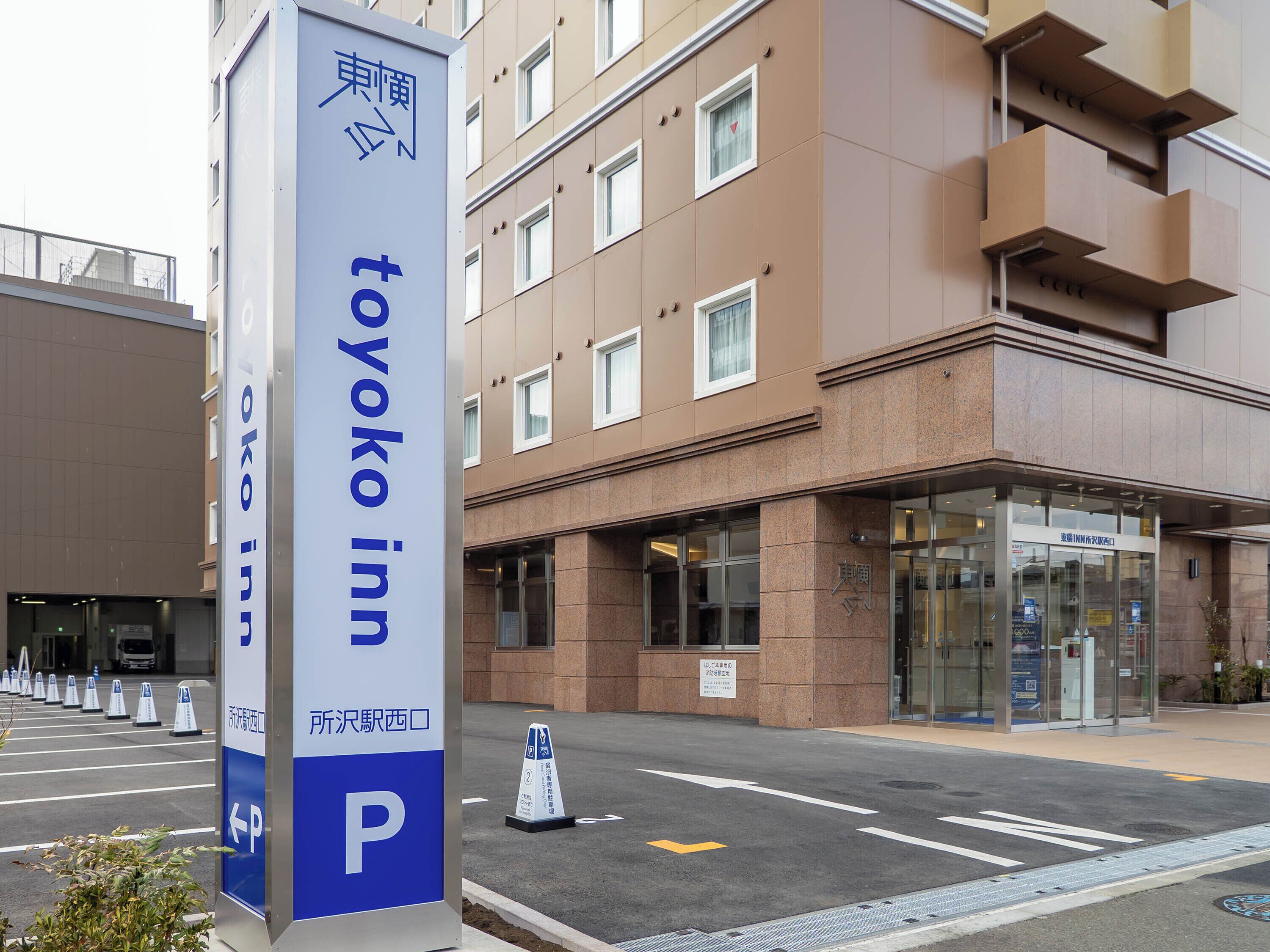 Een hotelschild met 'Toyako inn' en een parkeerschild met een naar links wijzende pijl.