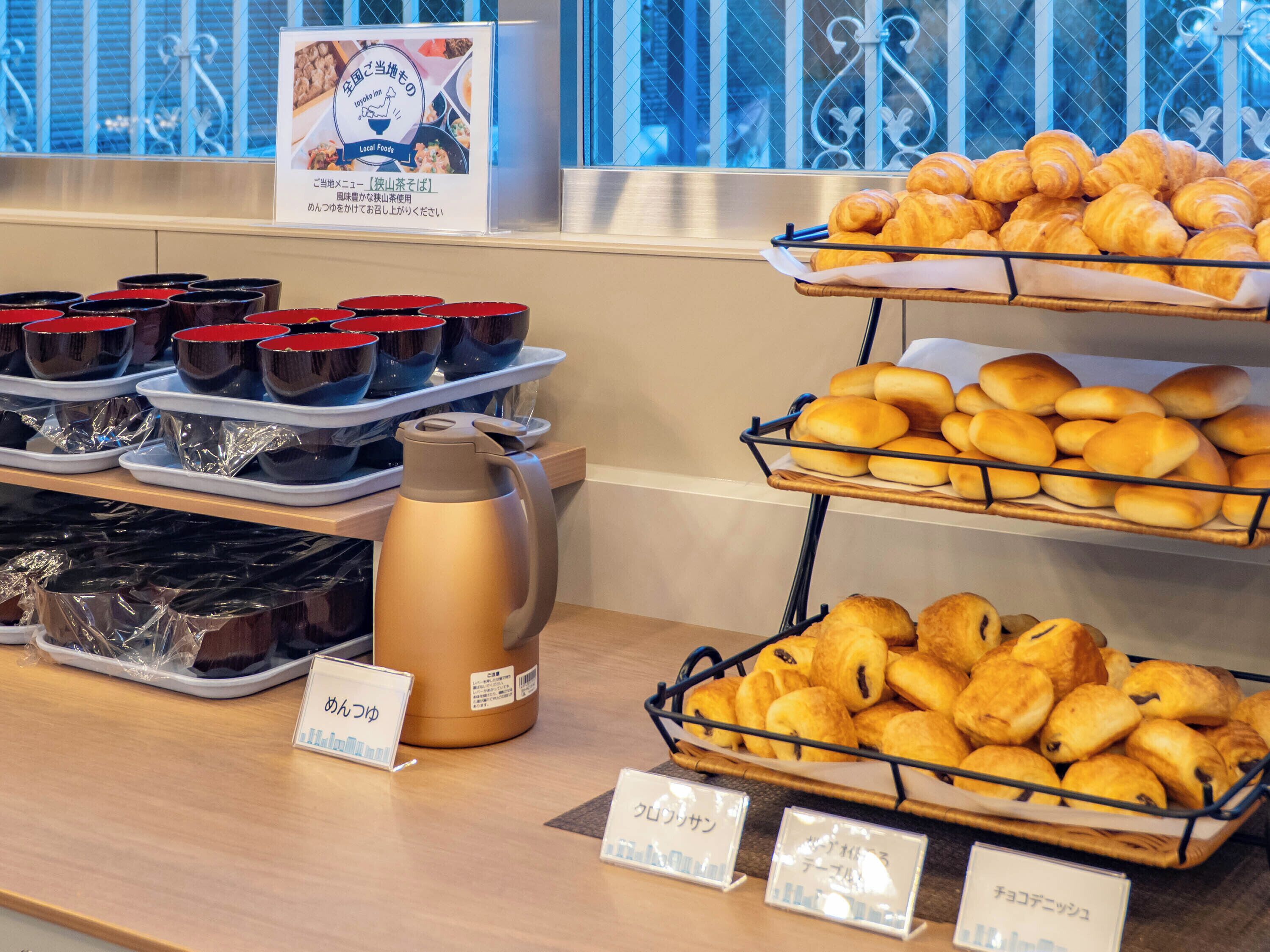 A buffet with various food items, including croissants and bread rolls, and a coffee pot.