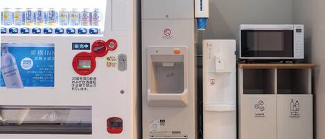 A vending machine with beverages, an ice dispenser, a microwave, and a water dispenser.