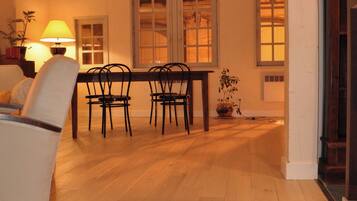 Een eetgedeelte met een houten tafel, stoelen, een lamp en een potplant.