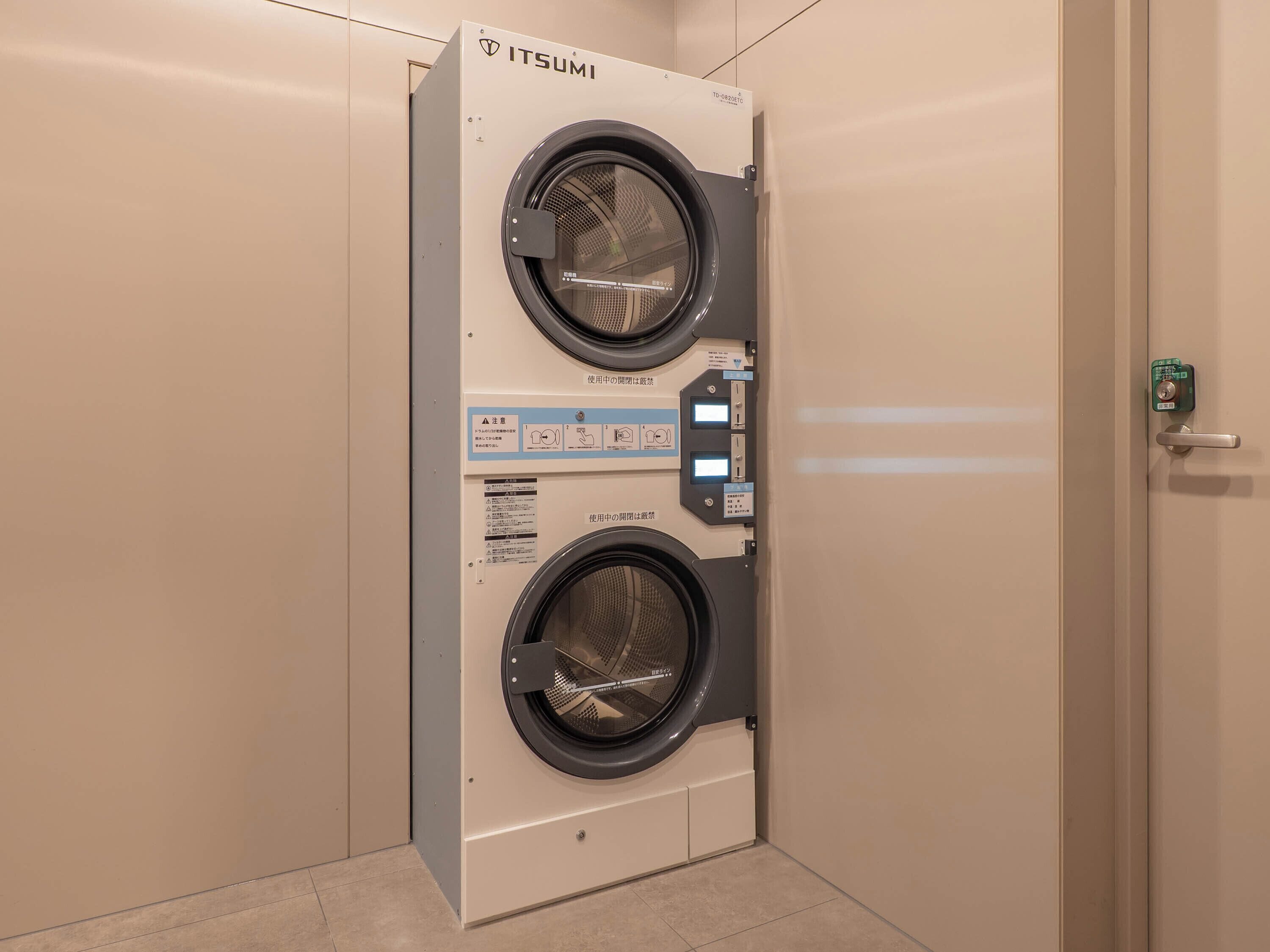 A wall-mounted, two-door, front-loading washing machine with control panel and safety instructions.