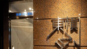 A hotel entrance with a sign in Japanese characters, a metal gate, and a granite wall. - Toyoko Inn Kochi (Kochi)