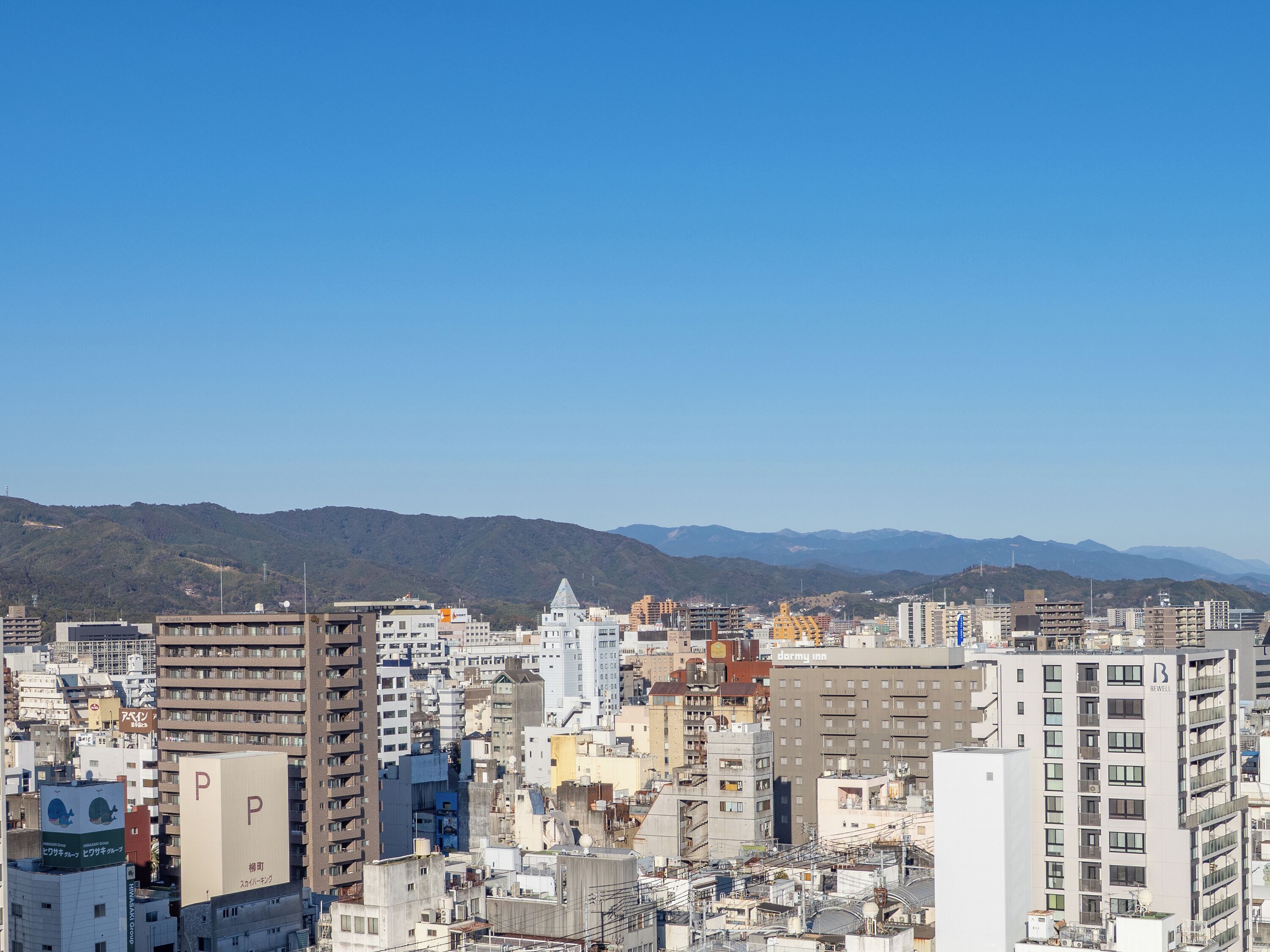 A cityscape with a variety of buildings, including a prominent hotel with a 'P' sign on the rooftop.