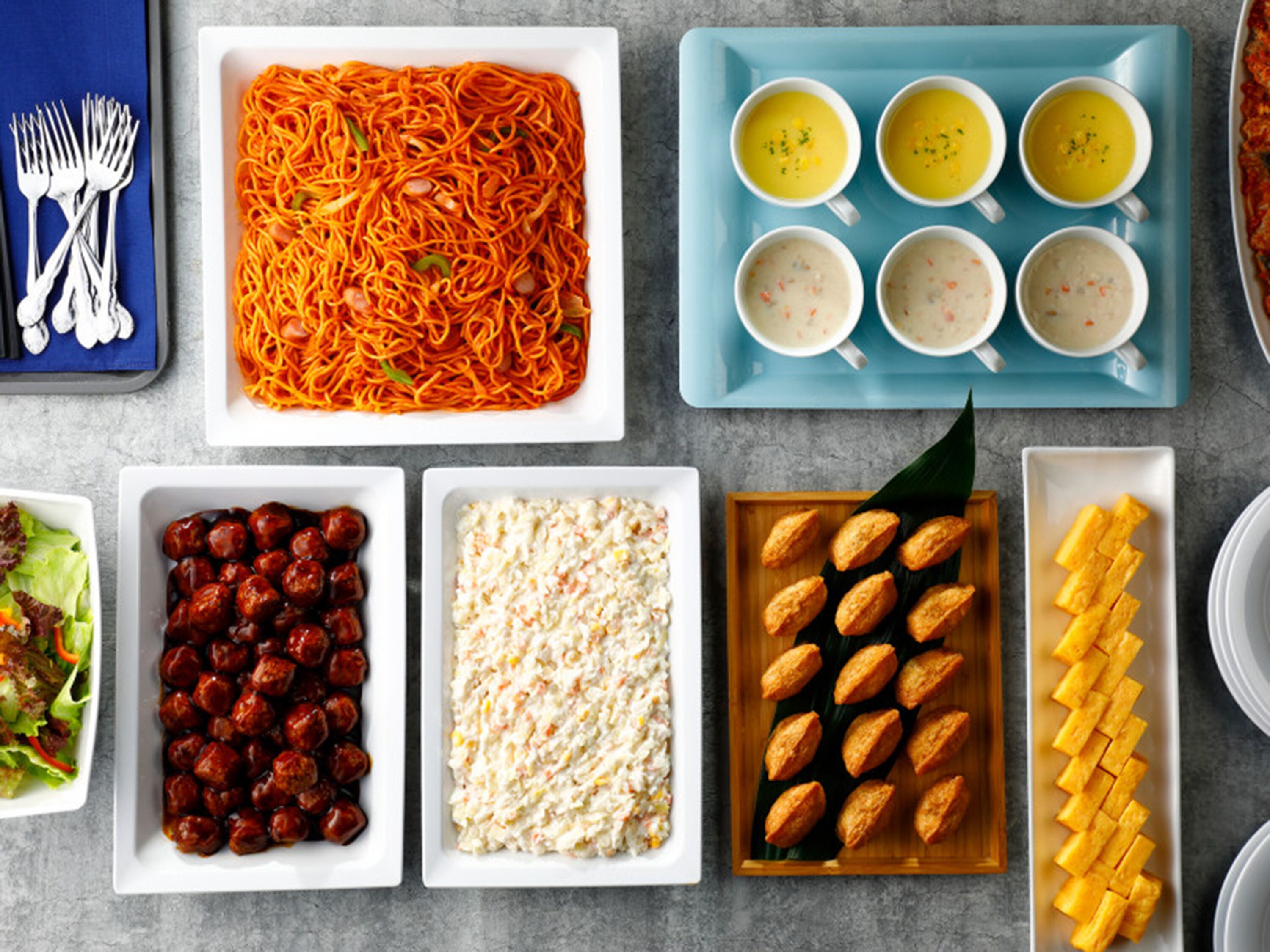 A variety of dishes including spaghetti, meatballs, salad, and bread.
