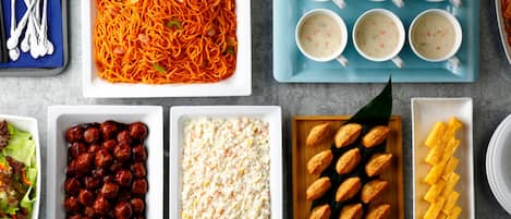 A variety of dishes including spaghetti, meatballs, salad, and bread.