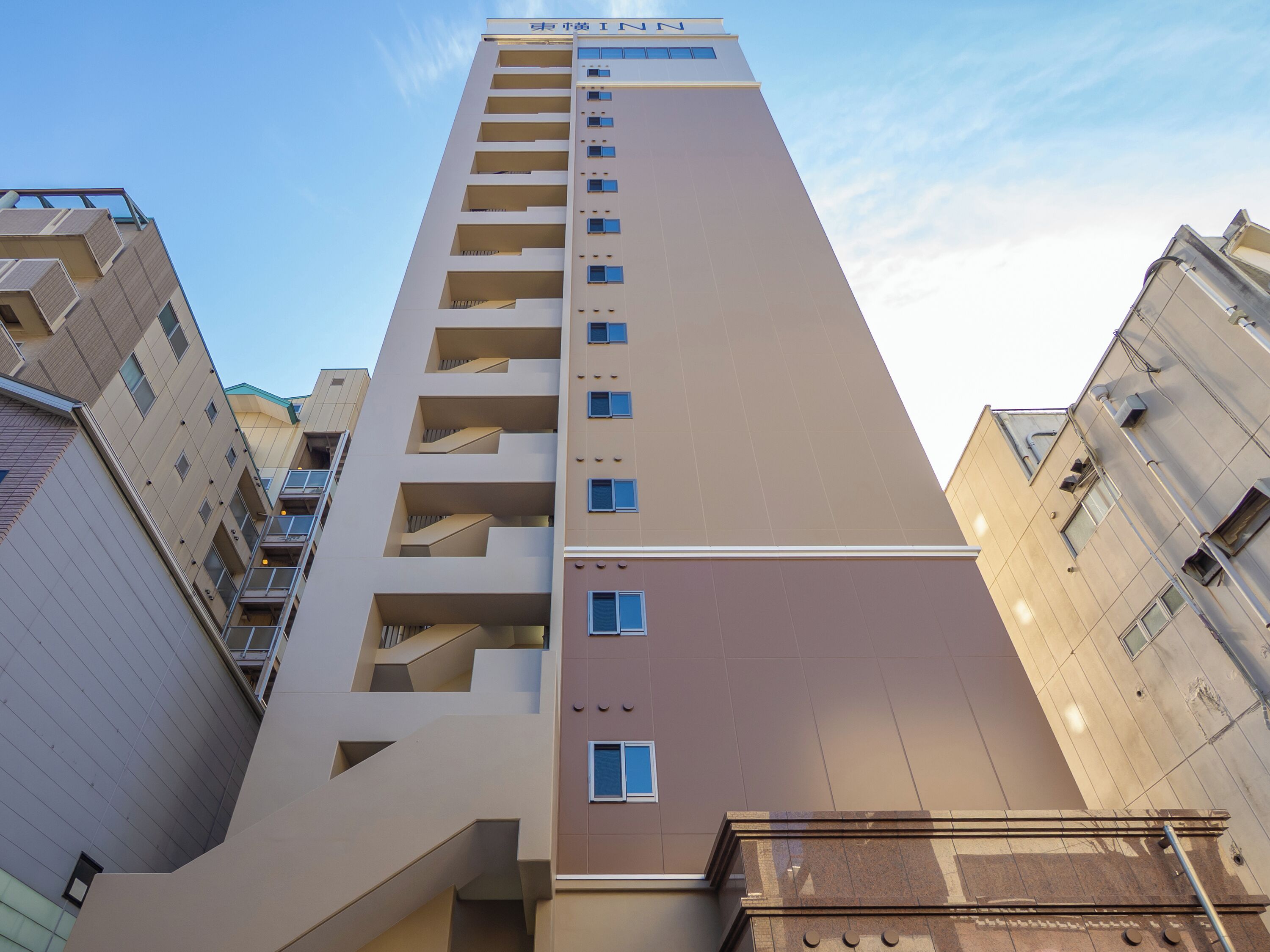 A high-rise building with multiple balconies and a clear sky.
