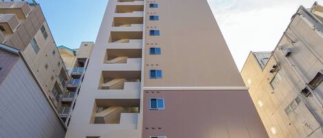 A high-rise building with multiple balconies and a clear sky.
