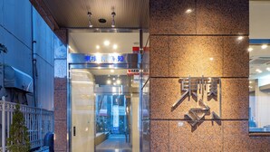 An entrance with a glass door, a metal sign with Chinese characters, and a tiled wall. - Toyoko Inn Kochi (Kochi)