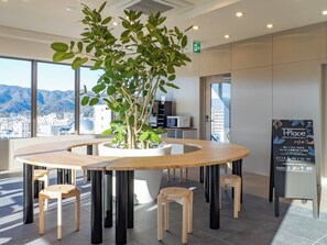 Un interior moderno con una mesa redonda rodeada de taburetes, una planta en maceta y un letrero.