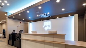 A reception desk with two Epson laptops, a digital sign with Chinese characters, and a modern interior with recessed lighting. - Toyoko Inn Kochi (Kochi)