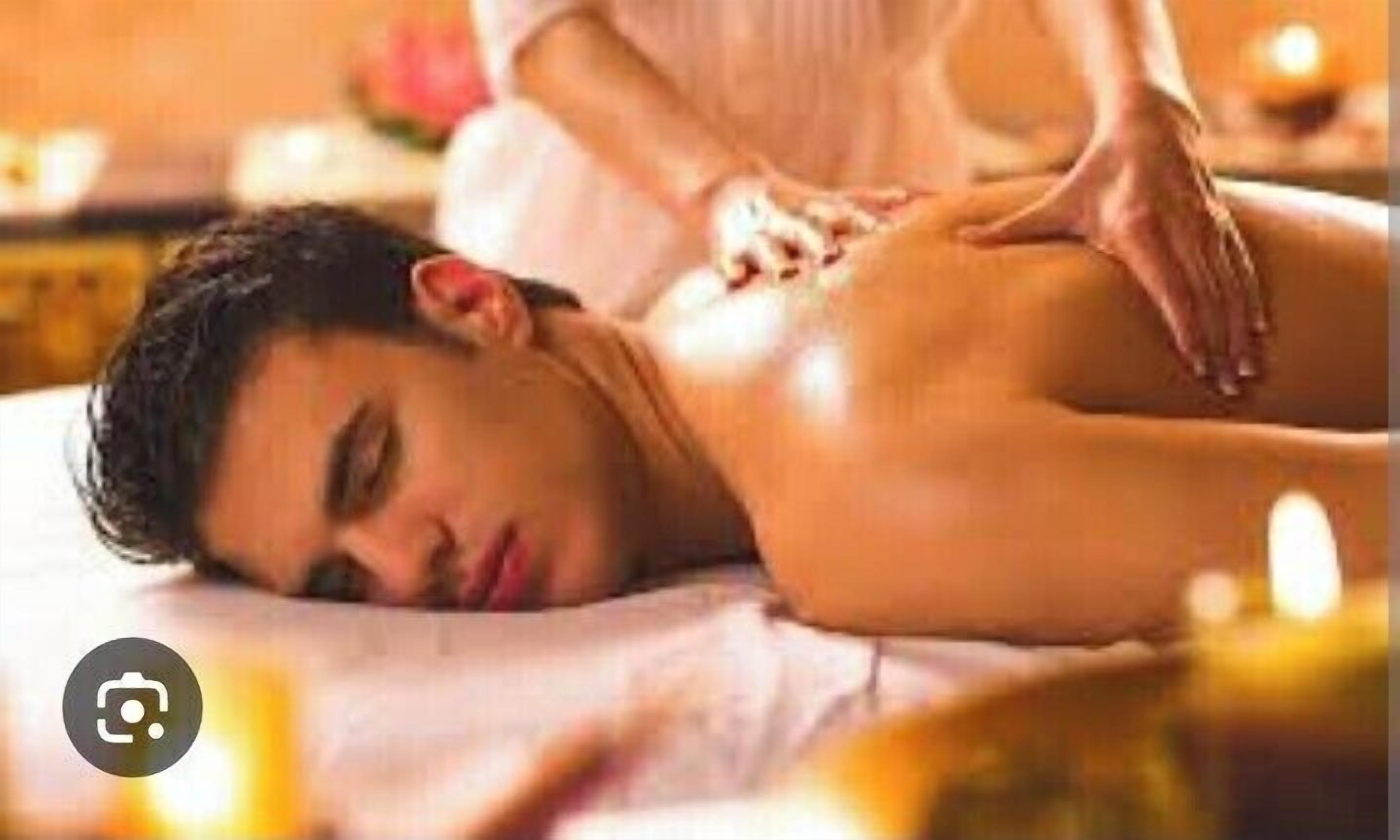 Een persoon geniet van een massage in een wellness omgeving, met kaarsen en een rustige sfeer.