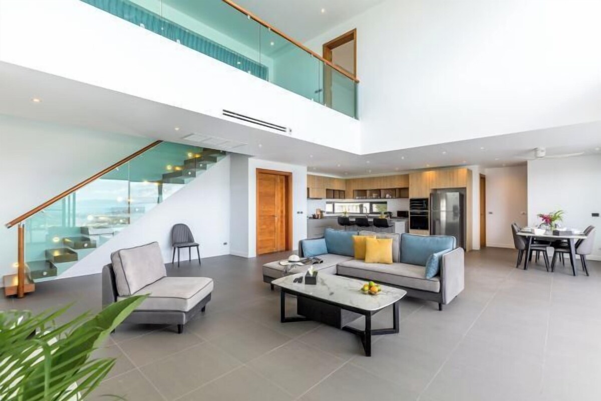 Un interior moderno con zona de estar, cocina y escalera.