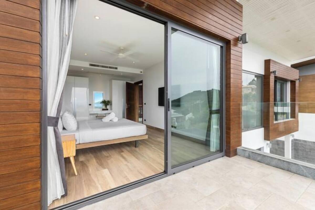 A modern bedroom with a bed, a sliding glass door, and a view of the city.