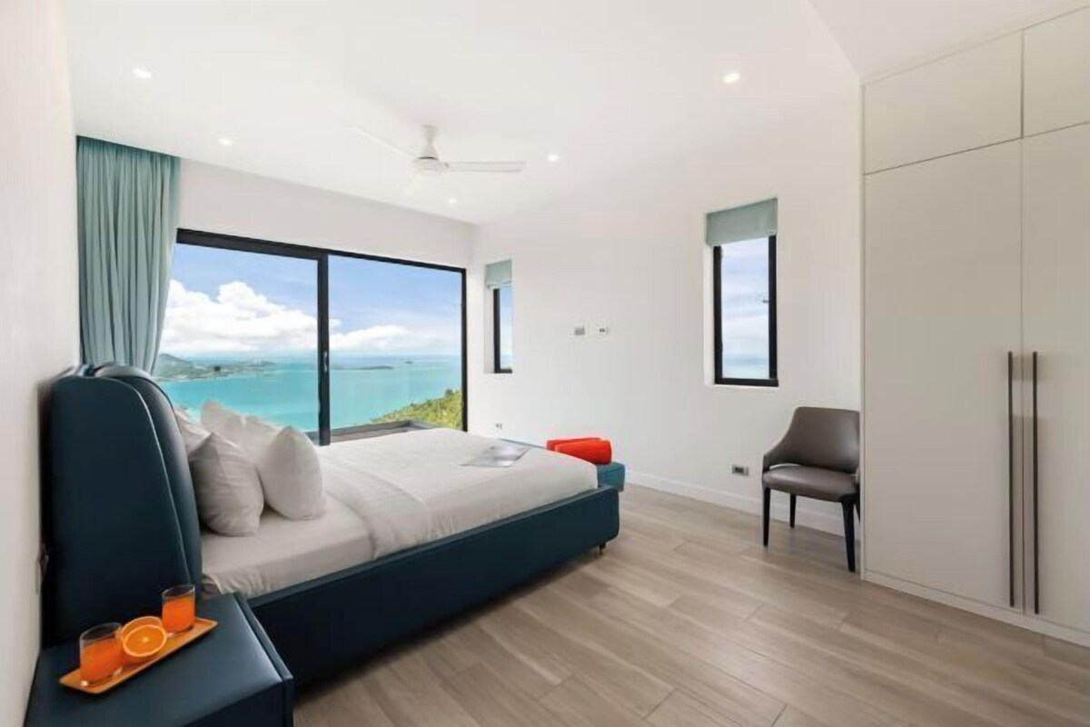Une chambre moderne avec une grande fenêtre, un lit, une chaise et une armoire.
