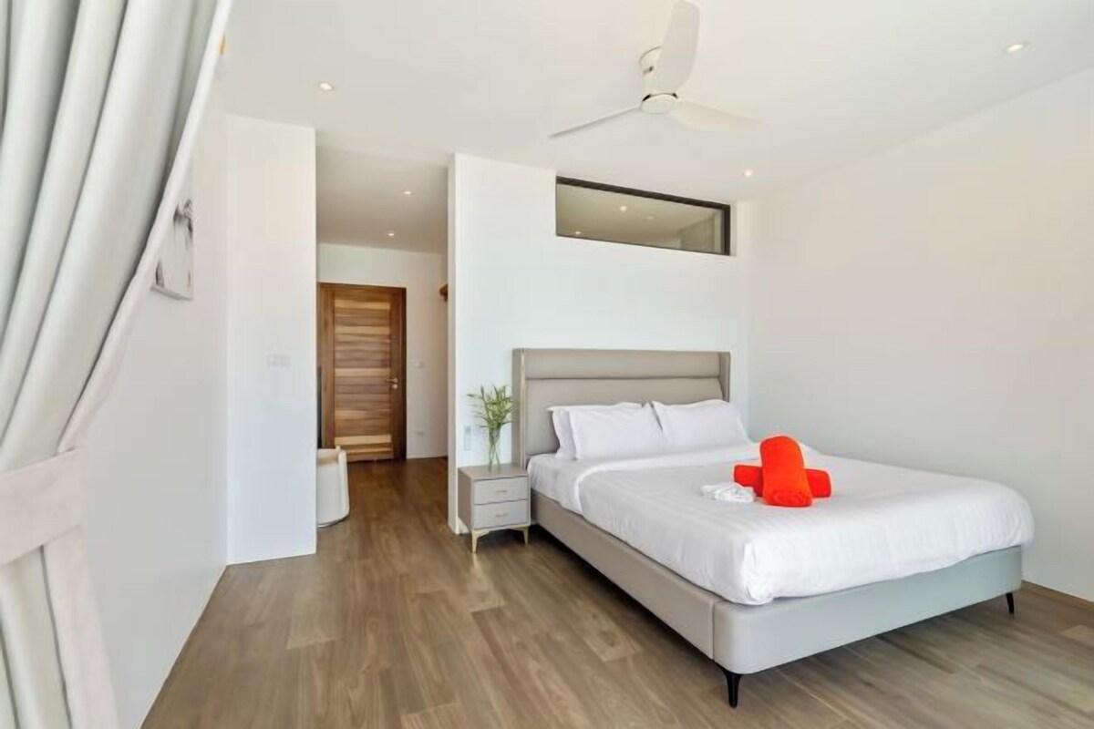 A modern bedroom with a bed, bedside table, and a ceiling fan.