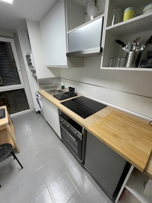 Een moderne keuken met een ingebouwde oven, vaatwasser en een houten aanrecht.