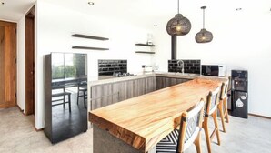 Une cuisine moderne avec un îlot central en bois, des appareils électroménagers noirs et des luminaires suspendus.