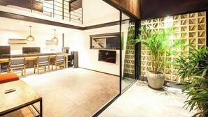 Un intérieur moderne comprenant une cuisine, un coin repas et une grande plante en pot.