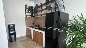 Una cocina compacta con un refrigerador negro, un lavamanos y armarios de madera.