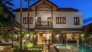 Une maison à deux étages dotée d’un balcon, d’une piscine et d’un espace extérieur bien éclairé.