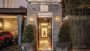 L’entrée de la villa se distingue par sa façade en pierre, une enseigne indiquant « Villa Annecy » et un chemin menant à la porte.